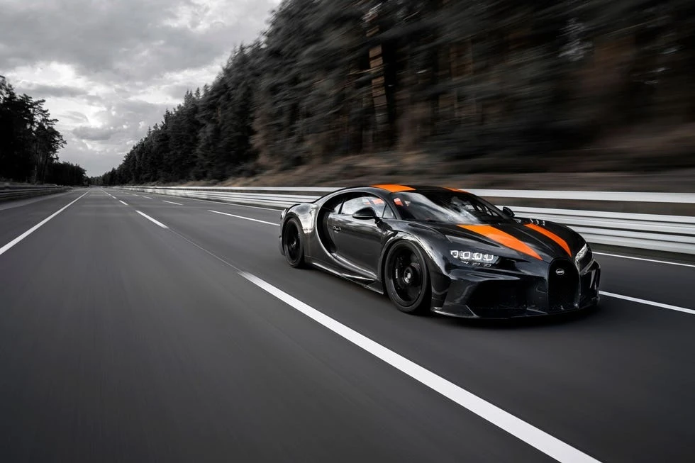 Bugatti Chiron на дороге на максимальной скорости, лес на фоне